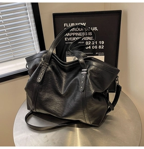 Detail of large black pebbled leather tote bag with metallic star rivets on table