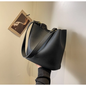 Détail d'un sac seau en cuir grainé noir avec boucles dorées et bandoulière large confortable