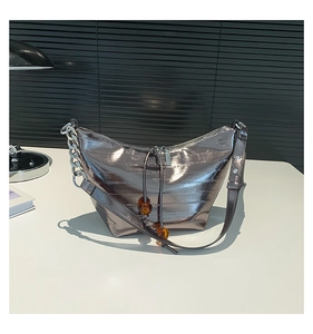 Detalle del bolso plateado metalizado con cuentas de ámbar y cadena de eslabones