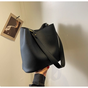 Détail du sac seau en cuir noir grainé avec ferrures dorées et logo embossé