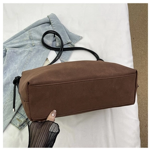 Vue détaillée du sac bandoulière en daim marron montrant les coutures et la bandoulière