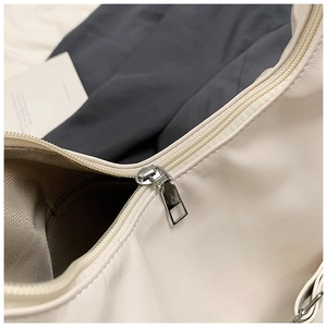 Detail of creamy white faux leather bag with silver zipper and herringbone lining