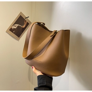 Détail du sac seau en cuir marron grainé avec ferrures dorées et logo de la marque