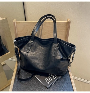 Detail of black faux leather tote bag with star rivets on a wooden chair