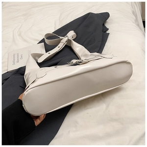 Detail view of smooth off-white PU leather shoulder bag with wide adjustable strap buckle