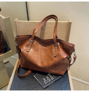 Detailed view of brown vintage leather tote bag with star rivets on a wooden seat