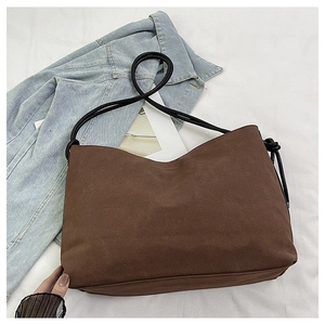 Détail du sac à bandoulière en daim mat marron foncé avec bandoulière en corde noire