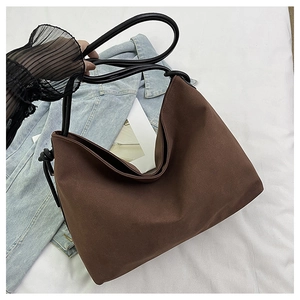 Détail du sac cabas en daim marron avec anses en corde noire et nœuds décoratifs