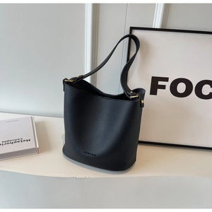 Détail du sac seau en cuir noir grainé avec des finitions dorées et logo de la marque