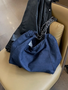 Deep blue denim chain tote bag with spacious design on a leather seat with jacket