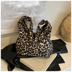 Close-up of leopard print canvas tote bag on a leather jacket with artistic props