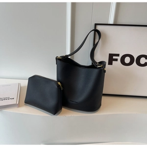 Détail du sac seau noir grainé avec ferrures dorées et pochette assortie incluse
