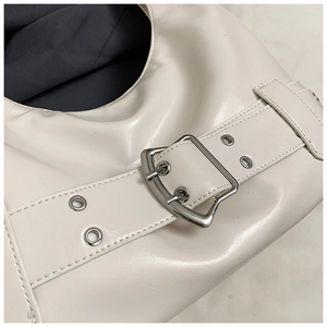 Close-up of cream faux leather shoulder bag featuring silver twin-needle metal buckles