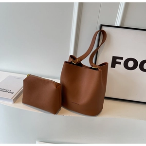 Détail du sac seau en cuir grainé marron foncé avec pochette assortie et boucles dorées