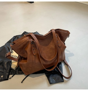 Detail of vintage brown leather tote bag with metal star rivets and durable dual handles