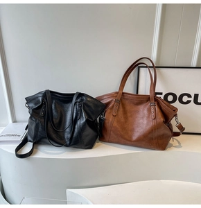 Detail view of large tote bags in black and brown faux leather with star metal rivets