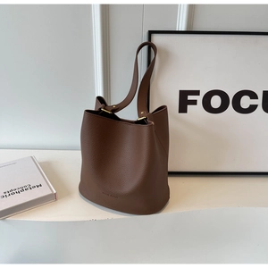 Détail du sac seau en cuir marron foncé montrant les ferrures dorées et la texture