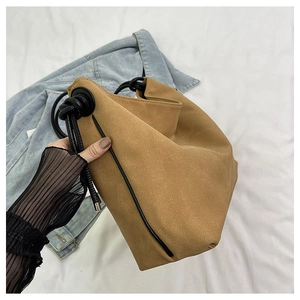 Détail du sac seau en daim camel avec poignées en corde noire et coutures minimalistes
