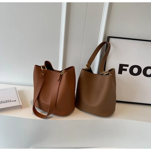Détail de la texture en cuir grainé de ces sacs seaux avec des boucles dorées