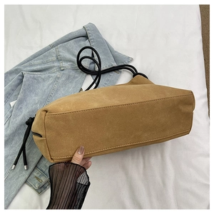 Détail du sac à bandoulière en daim marron avec cordon décoratif et fond large