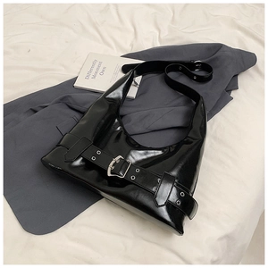 Detail of black glossy crescent shoulder bag with wide strap and silver metal buckle