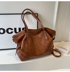 Close-up of brown retro leather tote bag featuring star rivets and a metallic finish