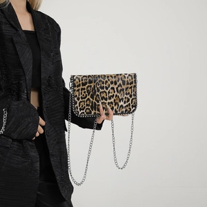 Detail view of leopard print crossbody bag with silver studs on a fashion model