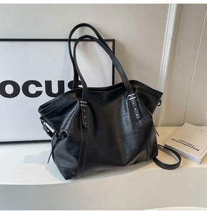 Close-up of black tote bag with silver star rivets and detailed lychee texture leather
