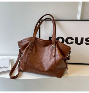Close-up of brown vintage faux leather tote bag with silver star rivets and detachable strap