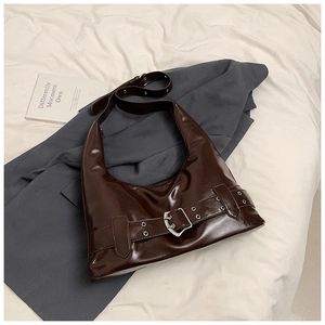 Detail of coffee brown glossy patent leather shoulder bag with bold silver buckle and metal eyelets