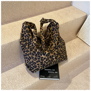 Detail of leopard print canvas bag with unique knotted handle on beige background