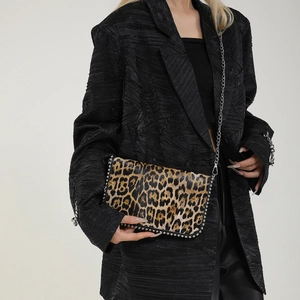 Detail of leopard print crossbody bag with silver rivet edges and metal chain strap