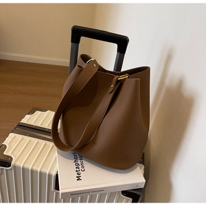 Détail du sac seau en cuir grainé marron caramel montrant la texture et le fermoir doré