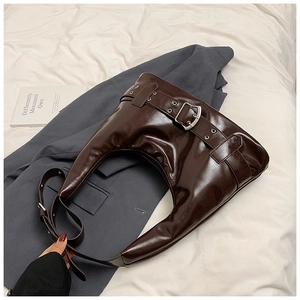 Detailed view of dark brown glossy patent leather hobo bag with large silver metal buckle