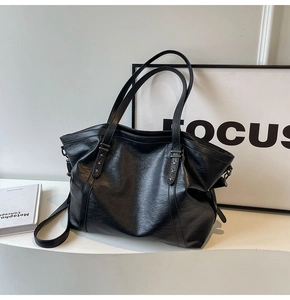 Black tote bag with star rivets and crinkled leather texture on minimalist display