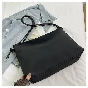 Détail d'un sac bandoulière minimaliste en nylon noir avec nœud et bandoulière fine