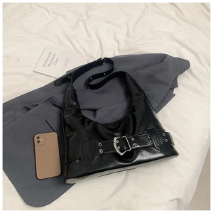 Detail of black glossy saddle bag with metal buckle straps on a grey suit blazer
