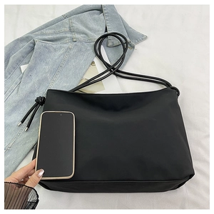 Comparaison de taille d'un sac bandoulière en nylon noir avec un smartphone pour capacité