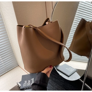 Détail du sac seau en cuir litchi marron caramel avec des finitions en métal doré