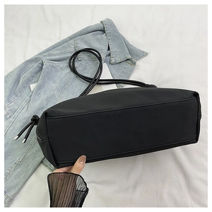 Détail d'un sac à bandoulière en nylon noir avec base solide et cordon de serrage argenté