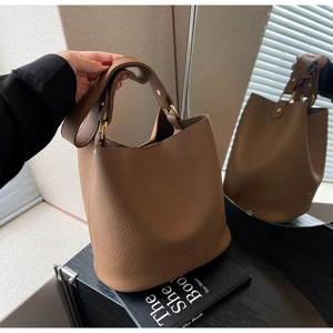 Gros plan du sac seau en cuir marron à motif litchi avec des ferrures dorées