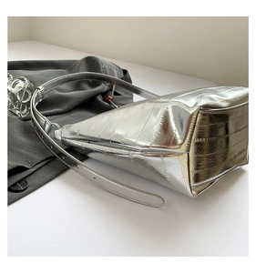 Primer plano del bolso plateado brillante con relieve de cocodrilo y textura metálica