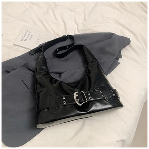 Detail of black glossy leather hobo bag with silver buckles and metal eyelets decoration