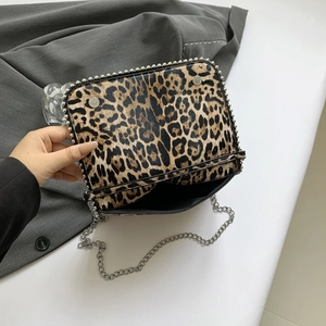 Detailed view of leopard print crossbody bag featuring silver studs and metal chain strap