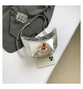 Detalle de bolso medialuna plateado metalizado con cuentas naranjas en blanco