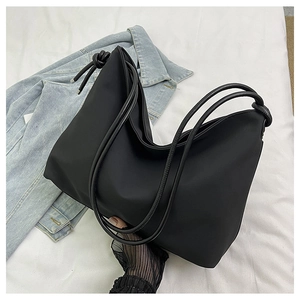 Détail du sac cabas en nylon noir avec doubles anses en corde et nœuds sur tissu blanc