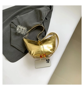 Vista superior de un bolso de media luna dorado texturizado con cordón y cuentas de ámbar
