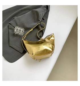 Detalle de bolso bandolera dorado metalizado con pliegues suaves y cadena de metal plateado