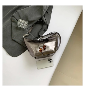 Detalle del bolso media luna plateado con cordón ajustable y detalles de cuentas de ámbar