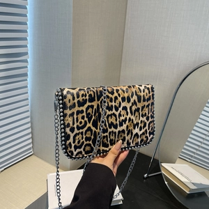 Detail of leopard print crossbody bag featuring silver rivet trim and metal chain strap